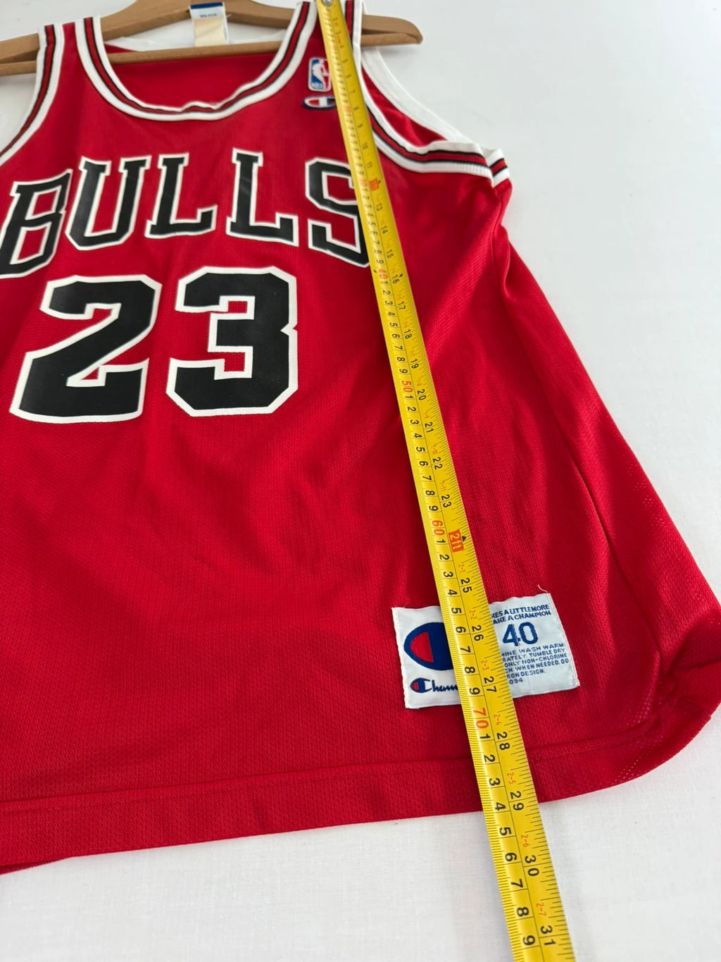 Champion red graphic tee featuring Jordan appliqué, NBA logo embroidery, and ribbed trim.
