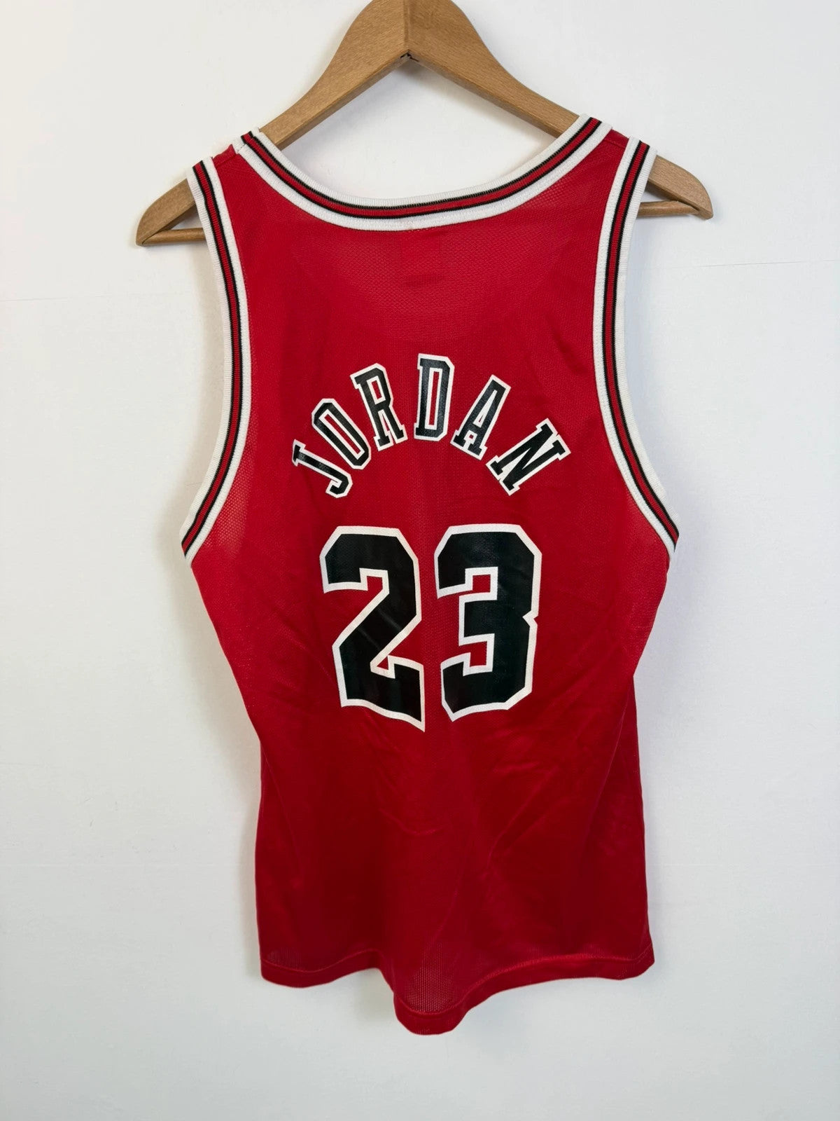 Champion red graphic tee featuring Jordan appliqué, NBA logo embroidery, and ribbed trim.
