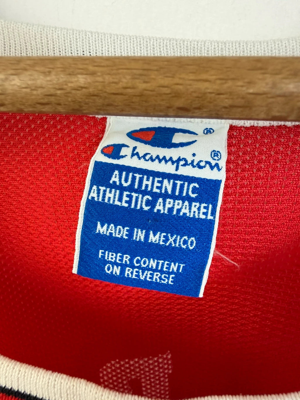 Champion red graphic tee featuring Jordan appliqué, NBA logo embroidery, and ribbed trim.