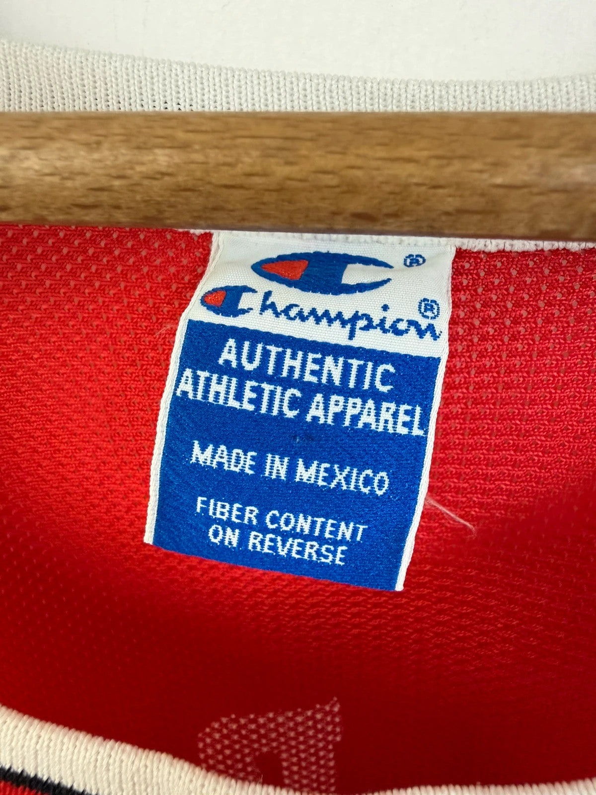 Champion red graphic tee featuring Jordan appliqué, NBA logo embroidery, and ribbed trim.