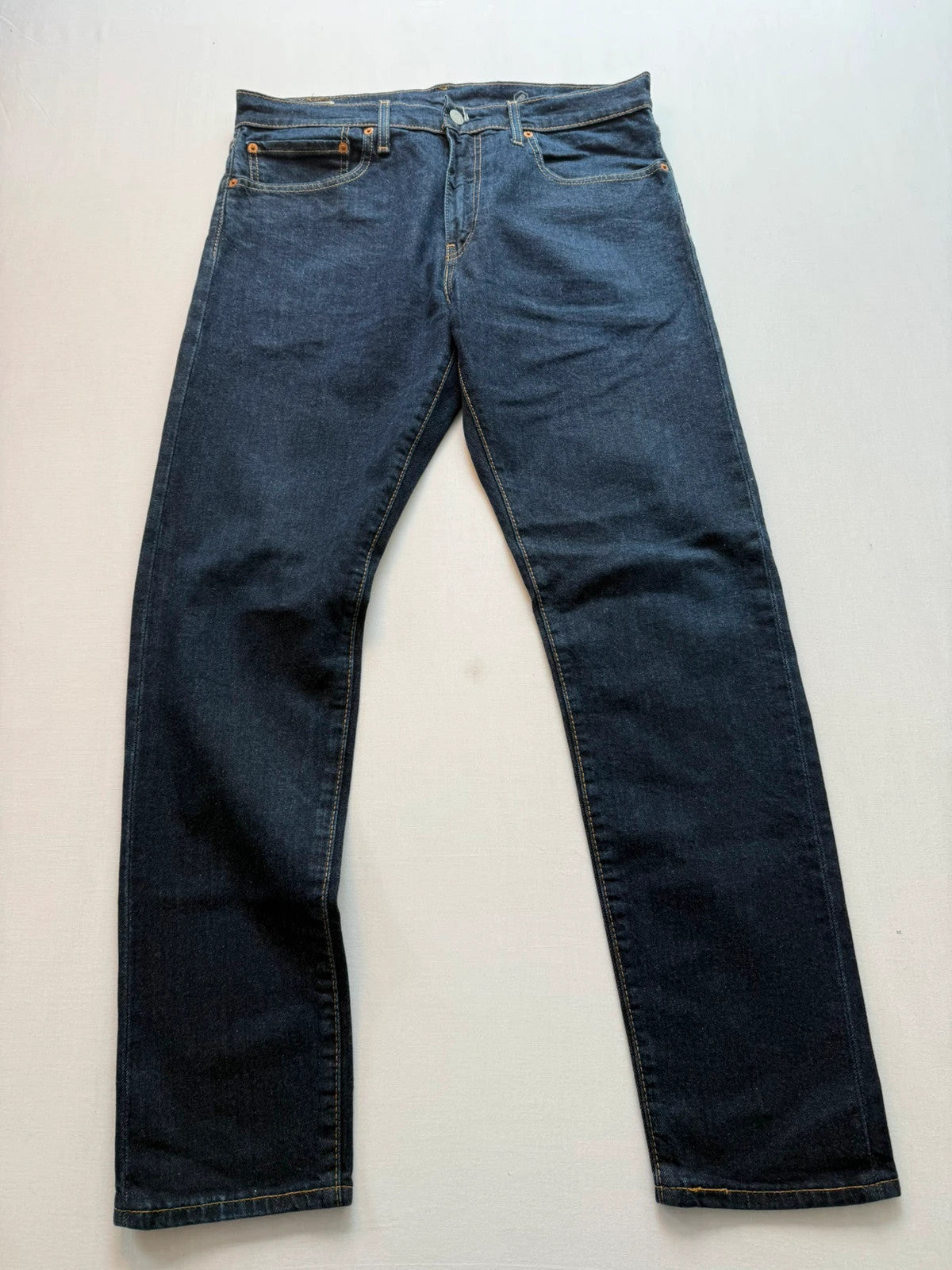 Levi's dark indigo slim taper jeans with classic five-pocket styling and signature stitching.