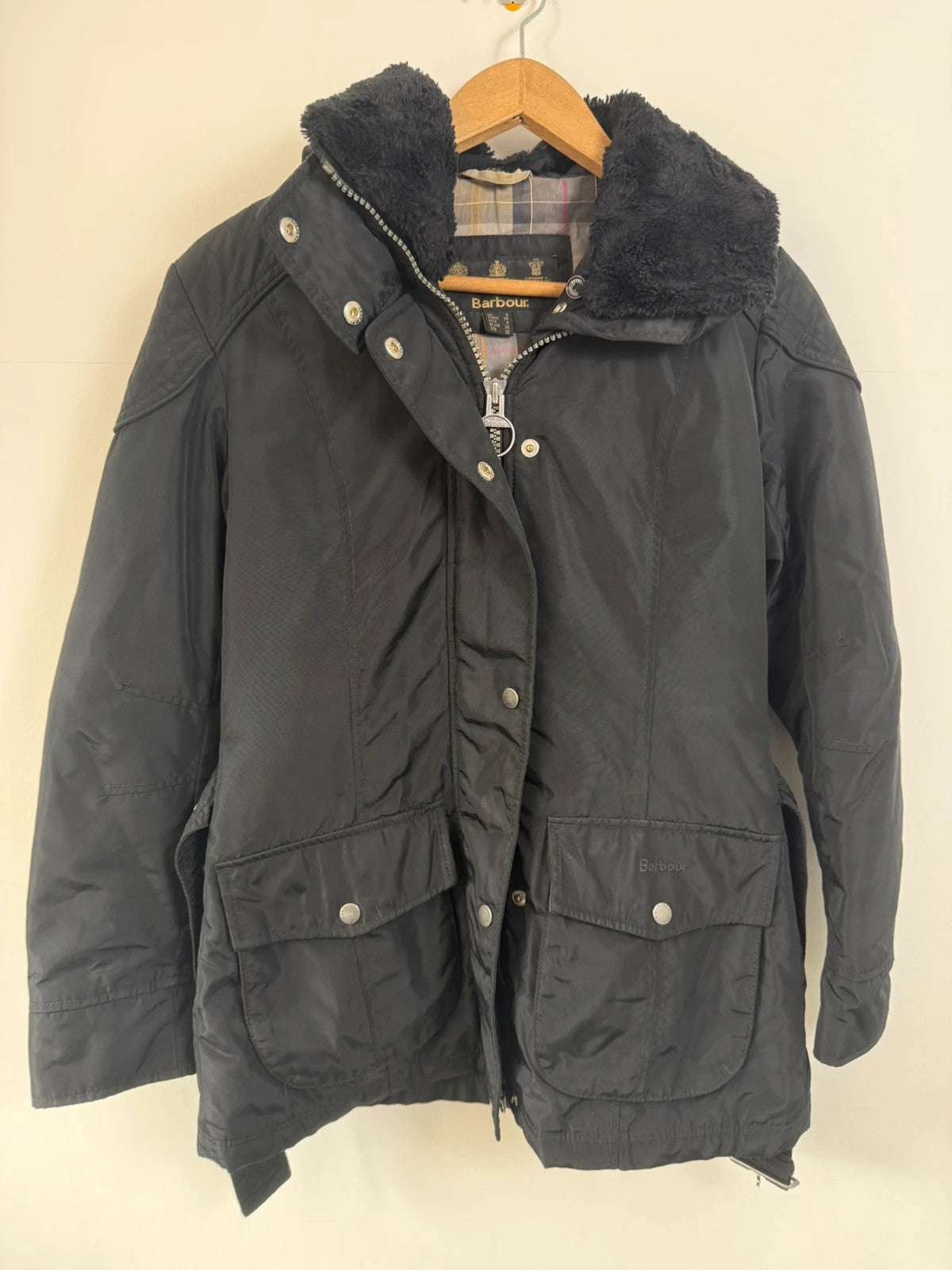 Barbour black waterproof jacket with faux fur collar, quilted shoulder panels, and tartan lining.