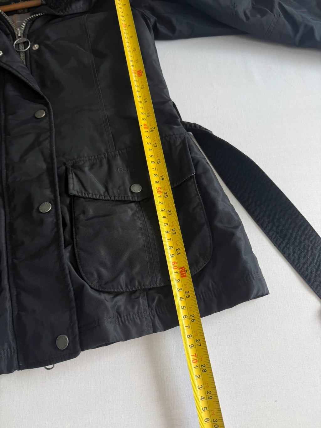 Barbour black waterproof jacket with faux fur collar, quilted shoulder panels, and tartan lining.