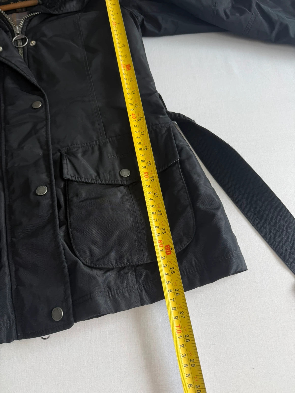 Barbour black waterproof jacket with faux fur collar, quilted shoulder panels, and tartan lining.