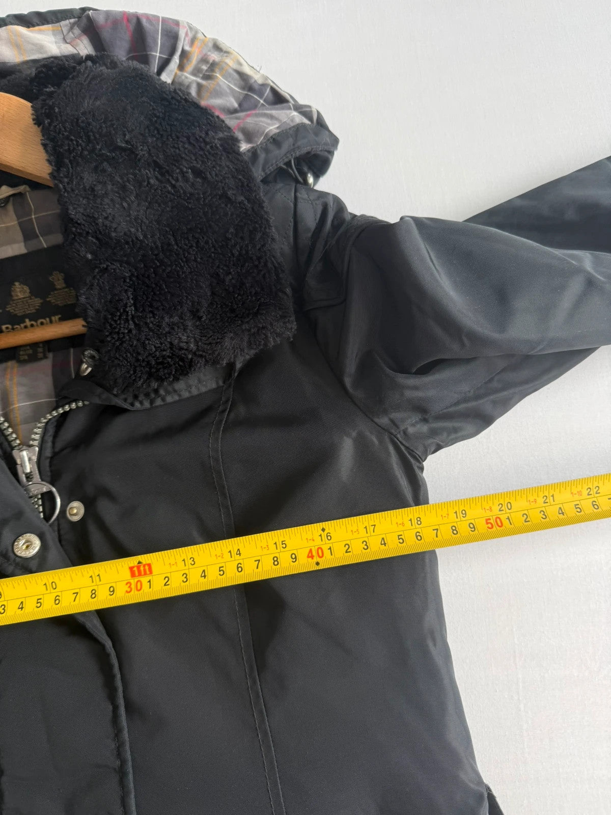 Barbour black waterproof jacket with faux fur collar, quilted shoulder panels, and tartan lining.