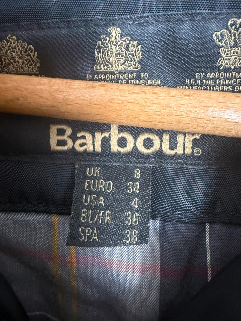 Barbour black waterproof jacket with faux fur collar, quilted shoulder panels, and tartan lining.