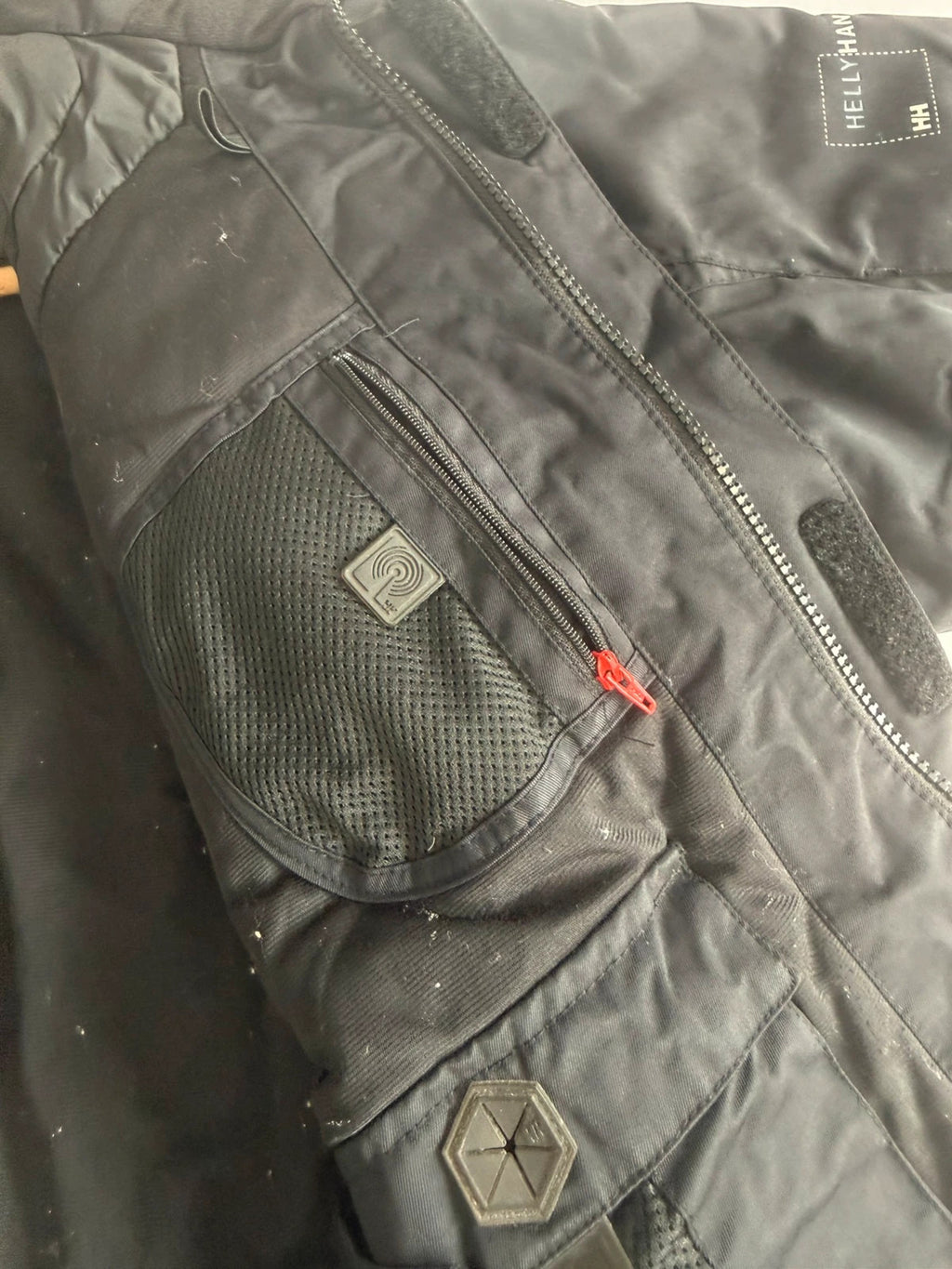 Helly Hansen black ski jacket with waterproof shell, mesh-vented pockets, and adjustable cuffs.