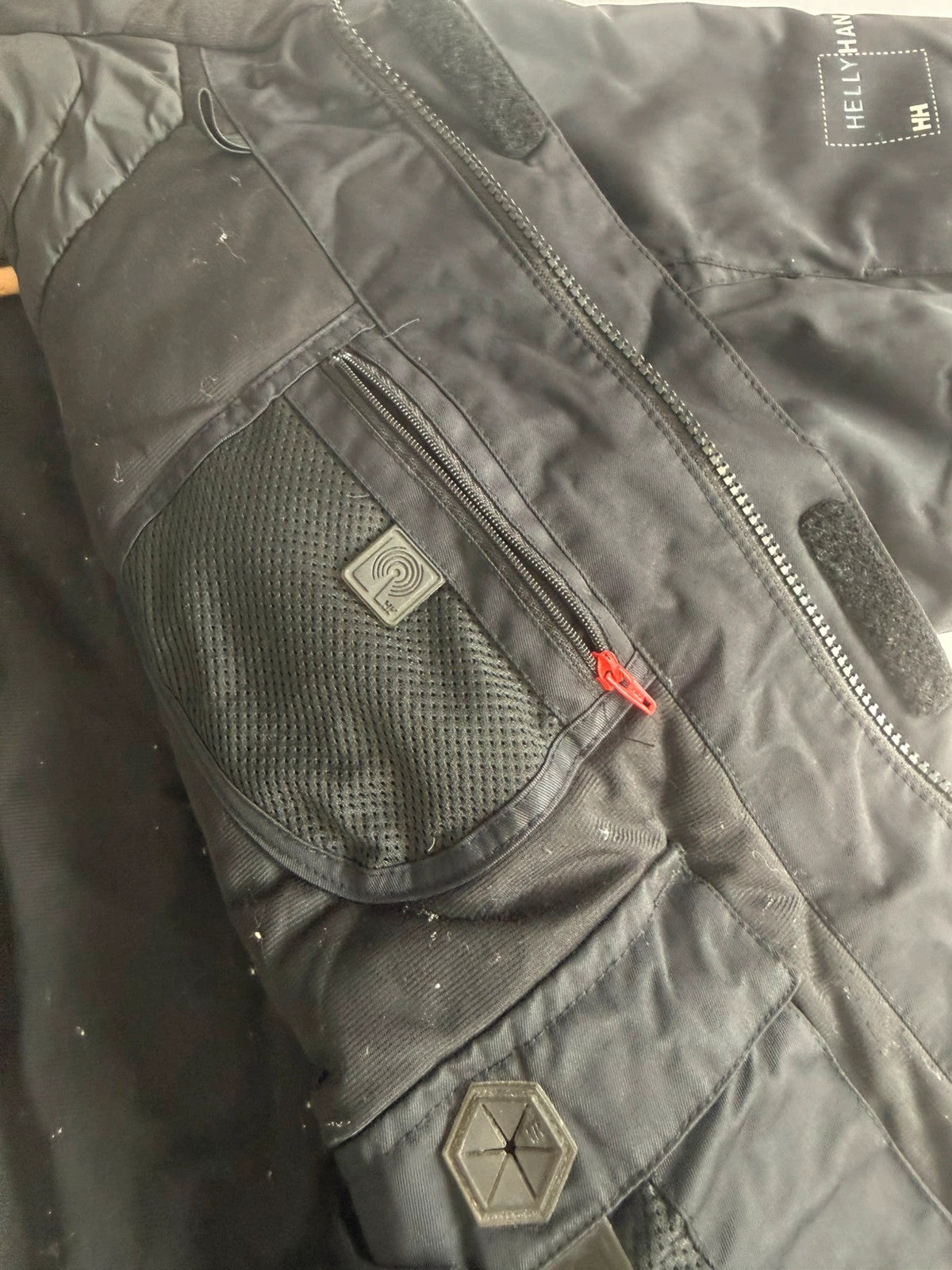 Helly Hansen black ski jacket with waterproof shell, mesh-vented pockets, and adjustable cuffs.
