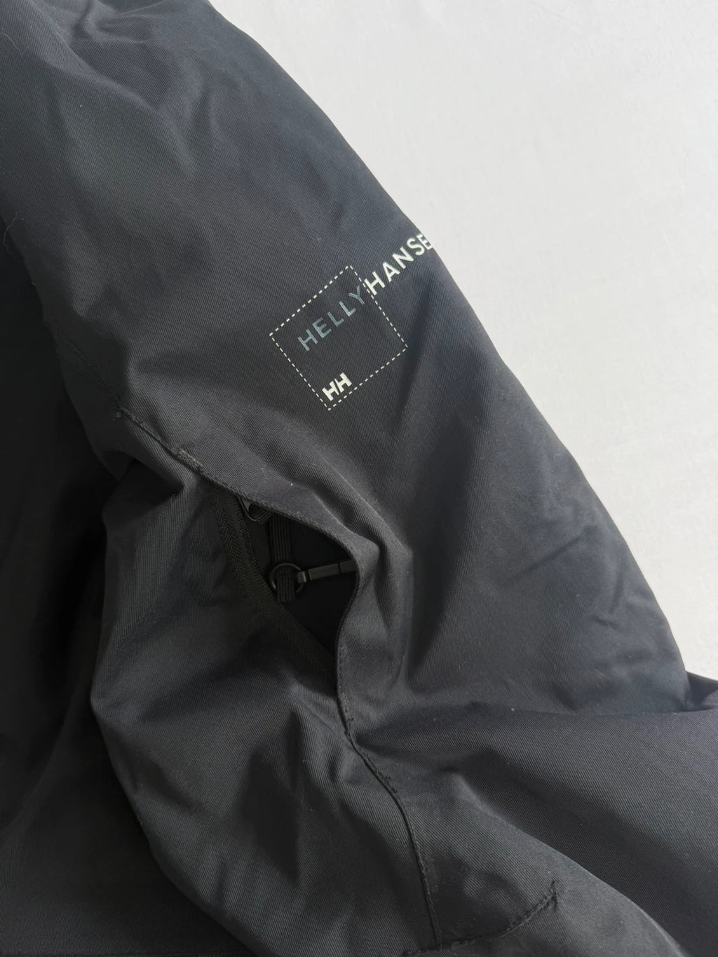 Helly Hansen black ski jacket with waterproof shell, mesh-vented pockets, and adjustable cuffs.