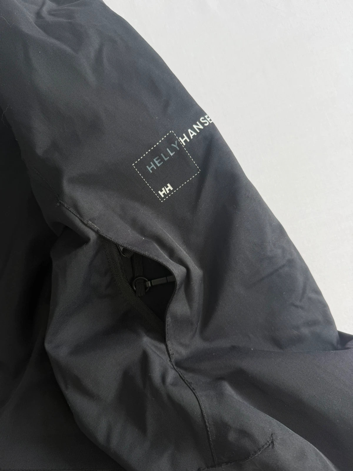 Helly Hansen black ski jacket with waterproof shell, mesh-vented pockets, and adjustable cuffs.