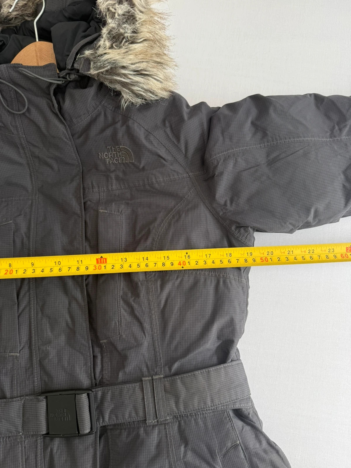 The North Face grey parka with adjustable faux fur hood and belted waist.