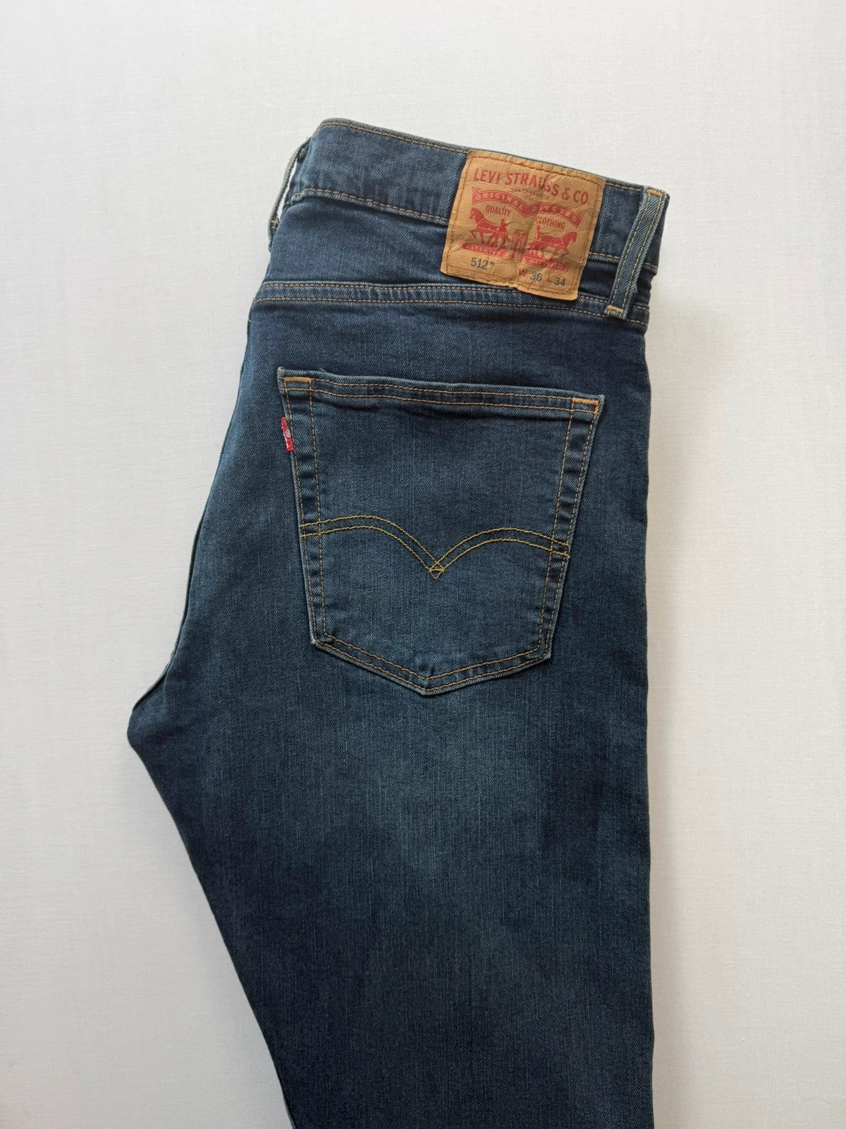 Levi's navy slim tapered jeans with faded blue-grey wash and signature back stitching.