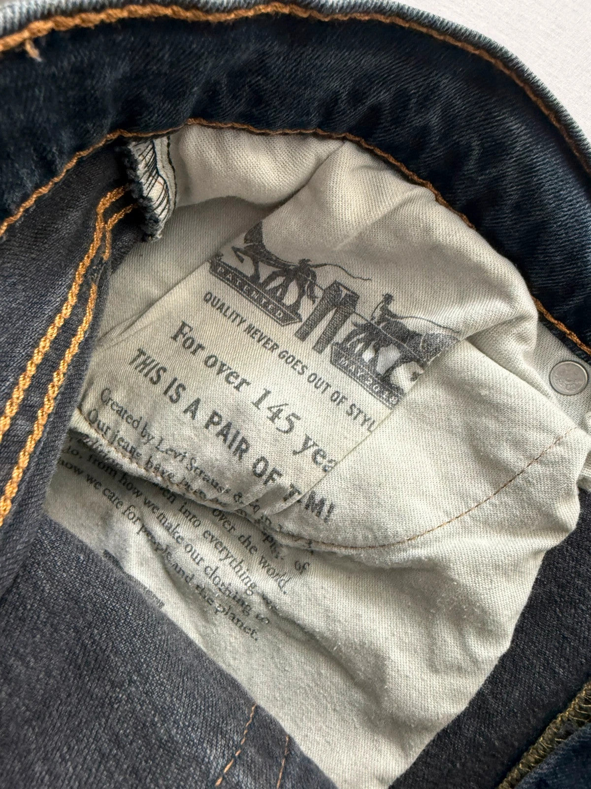 Levi's navy slim tapered jeans with faded blue-grey wash and signature back stitching.