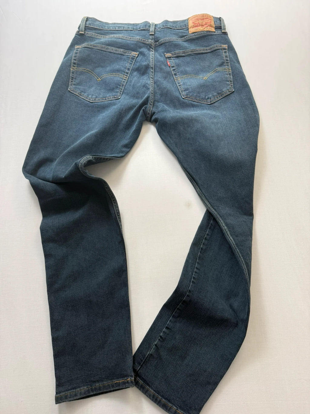 Levi's navy slim tapered jeans with faded blue-grey wash and signature back stitching.