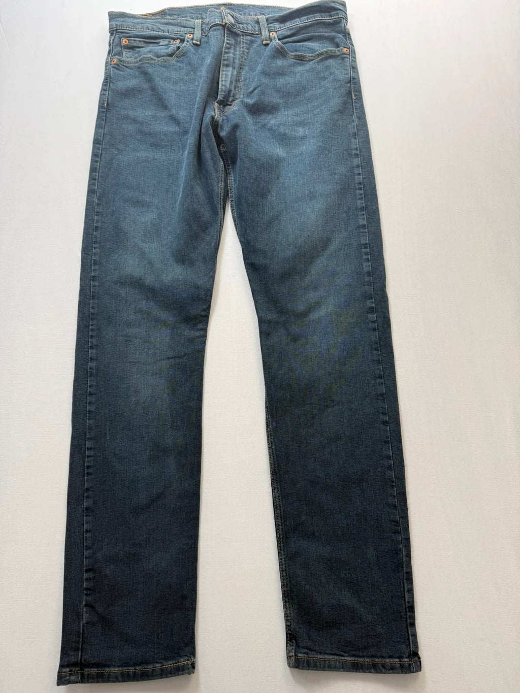 Levi's navy slim tapered jeans with faded blue-grey wash and signature back stitching.