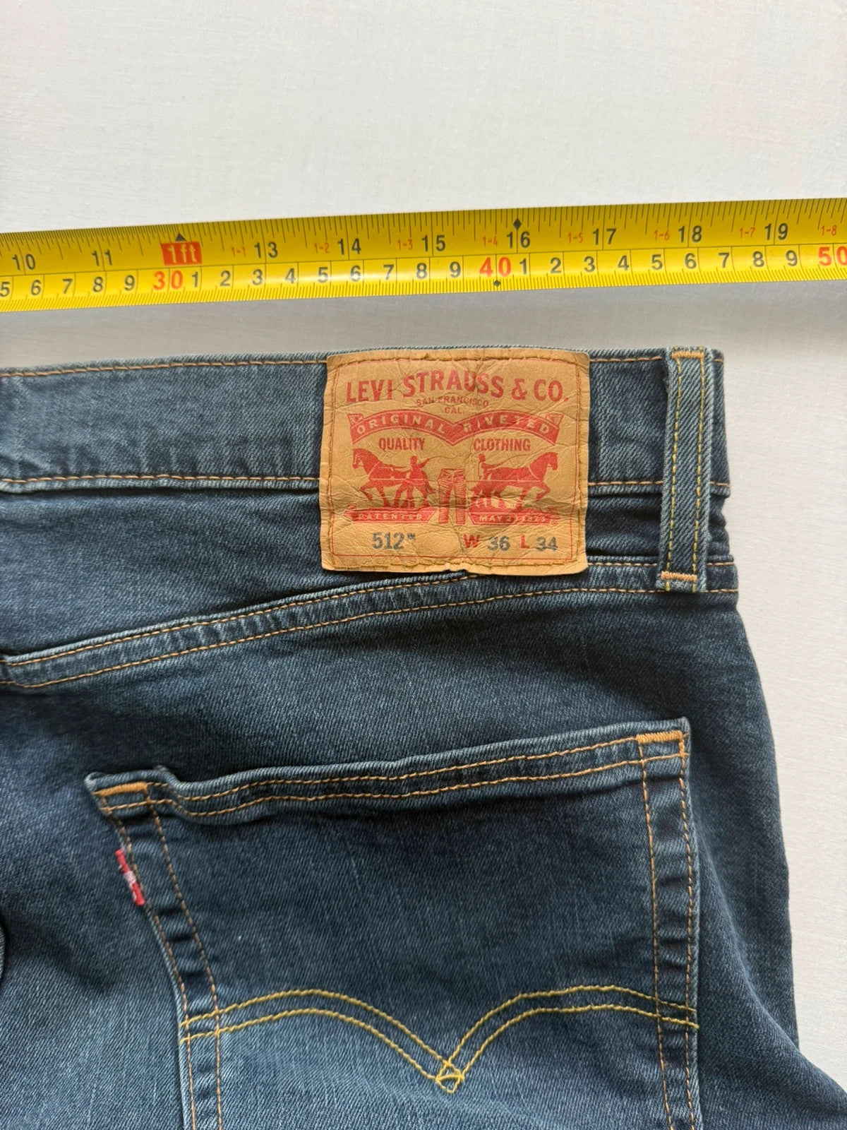 Levi's navy slim tapered jeans with faded blue-grey wash and signature back stitching.