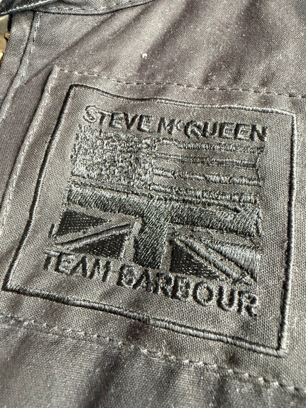 Barbour black waxed cotton biker jacket with embroidered Team Barbour patch and American flag lining.