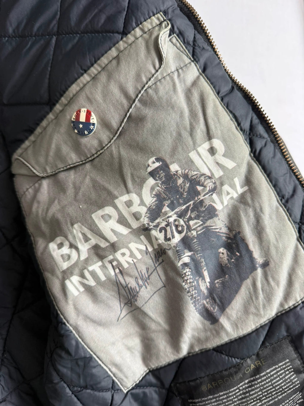 Barbour black waxed cotton biker jacket with embroidered Team Barbour patch and American flag lining.