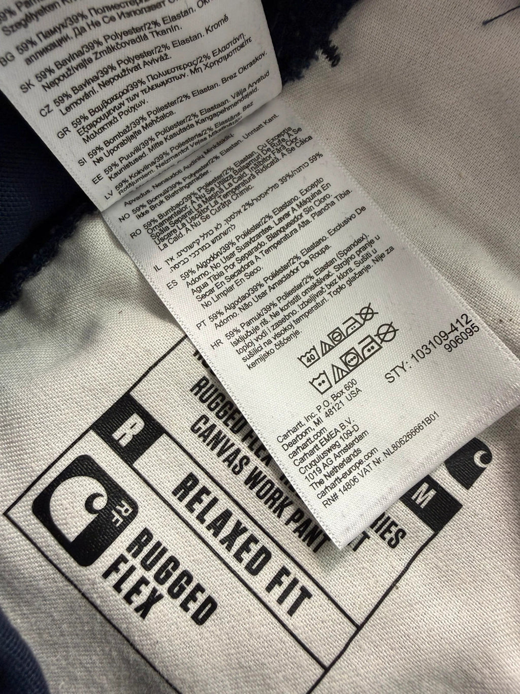 Carhartt navy work trousers with reinforced knees, multiple pockets, and Rugged Flex stretch.