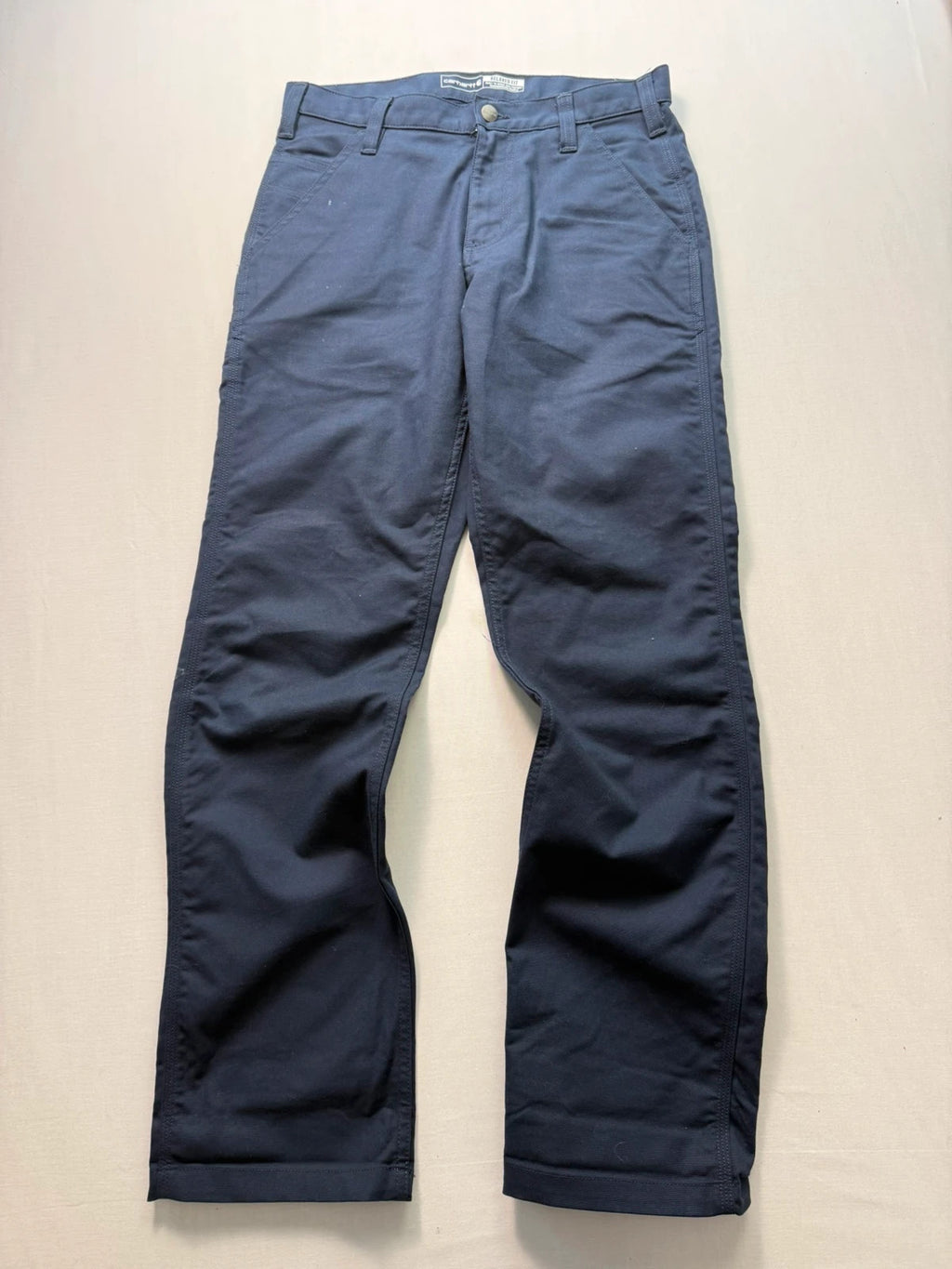 Carhartt navy work trousers with reinforced knees, multiple pockets, and Rugged Flex stretch.