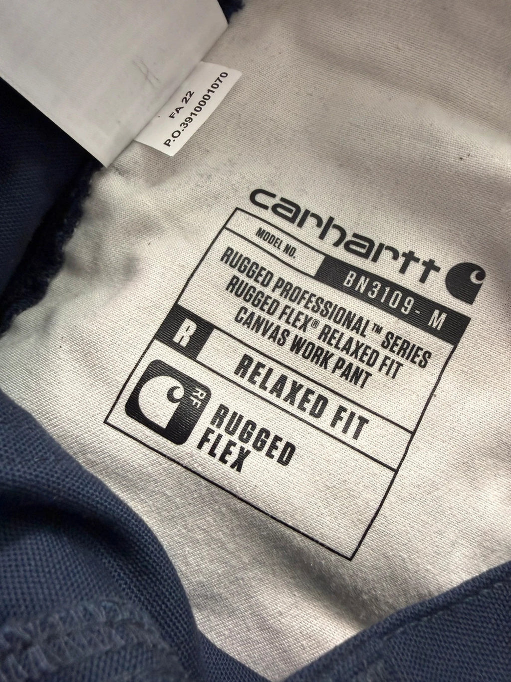 Carhartt navy work trousers with reinforced knees, multiple pockets, and Rugged Flex stretch.