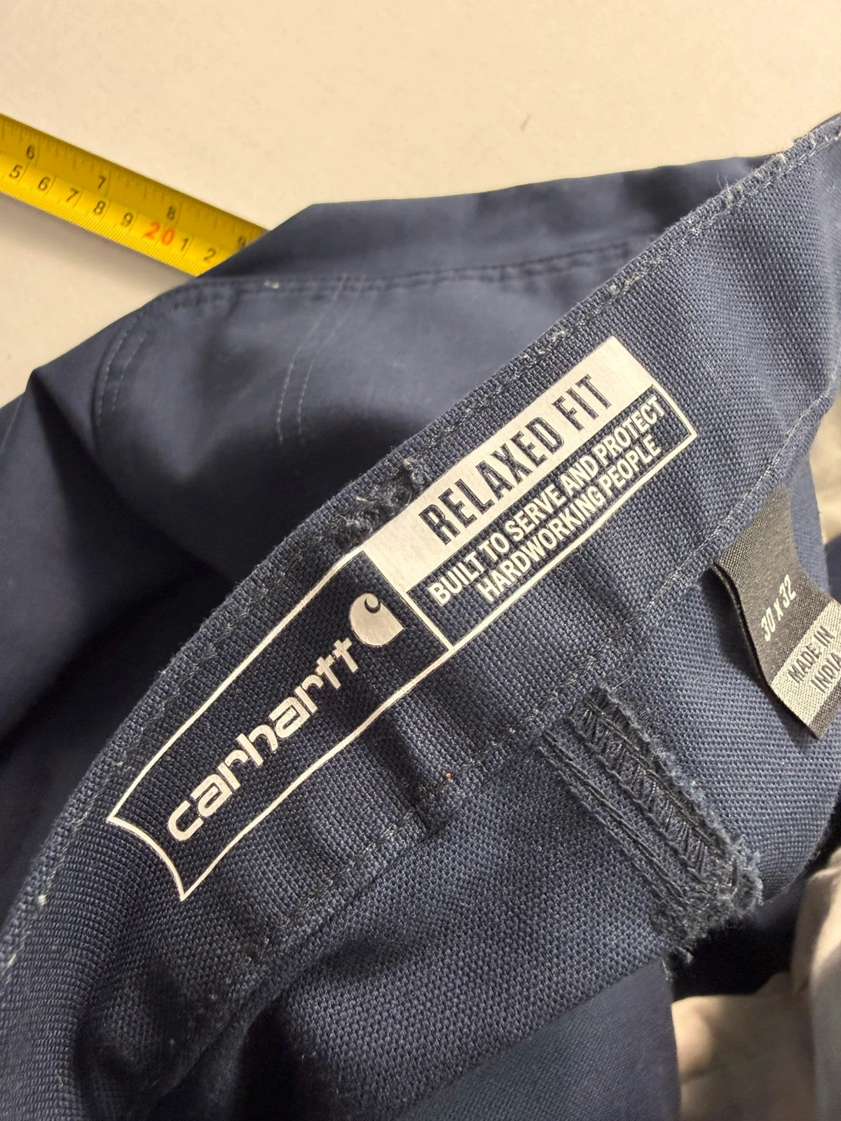 Carhartt navy work trousers with reinforced knees, multiple pockets, and Rugged Flex stretch.