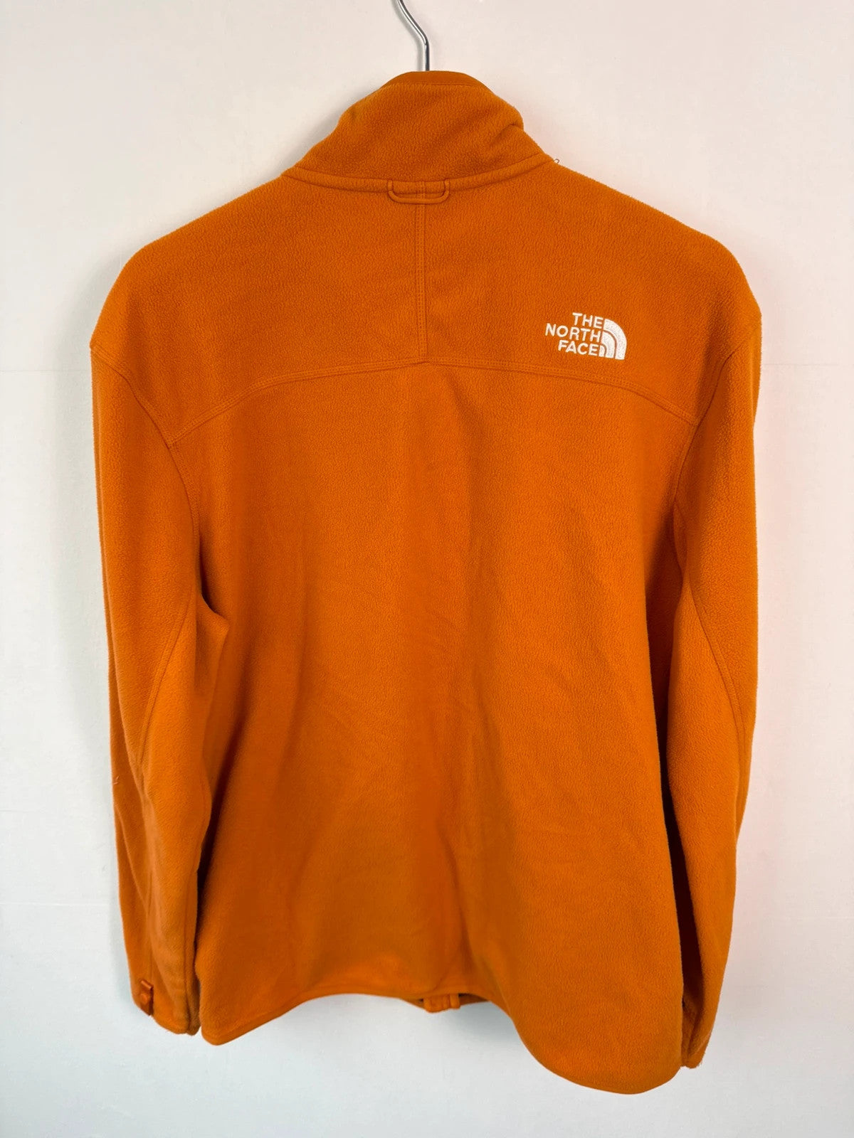 The North Face orange fleece jacket with embroidered logo and high stand collar.