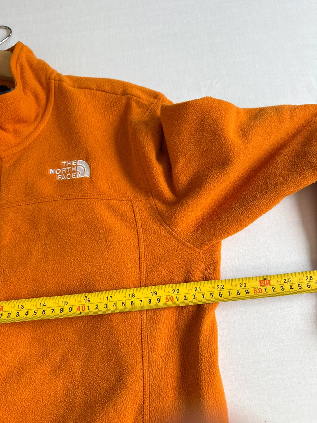 The North Face orange fleece jacket with embroidered logo and high stand collar.