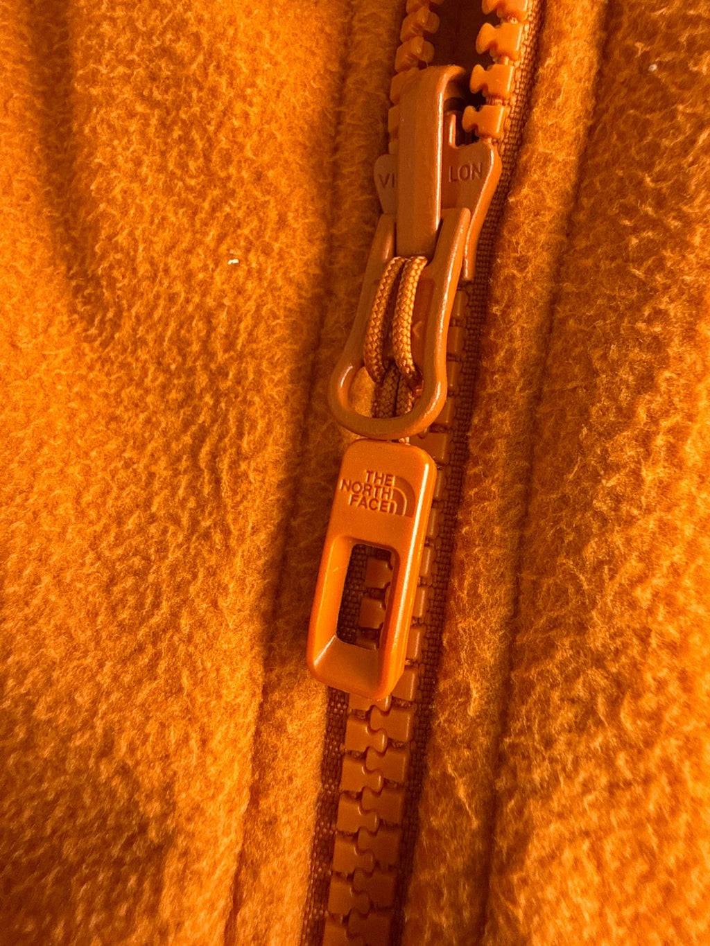 The North Face orange fleece jacket with embroidered logo and high stand collar.