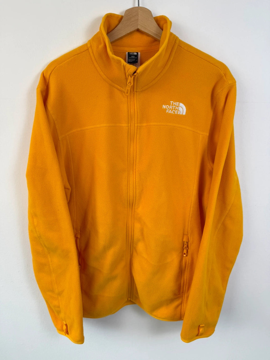 The North Face yellow fleece jacket with embroidered logo and zippered pockets.