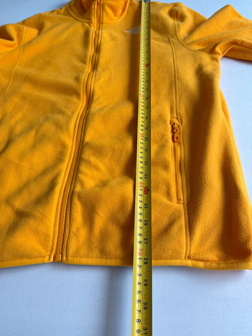 The North Face yellow fleece jacket with embroidered logo and zippered pockets.
