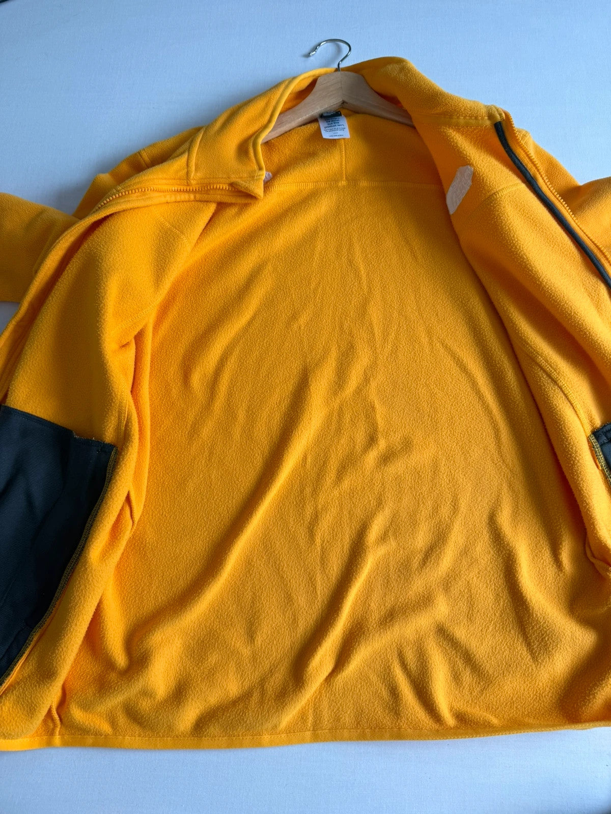The North Face yellow fleece jacket with embroidered logo and zippered pockets.