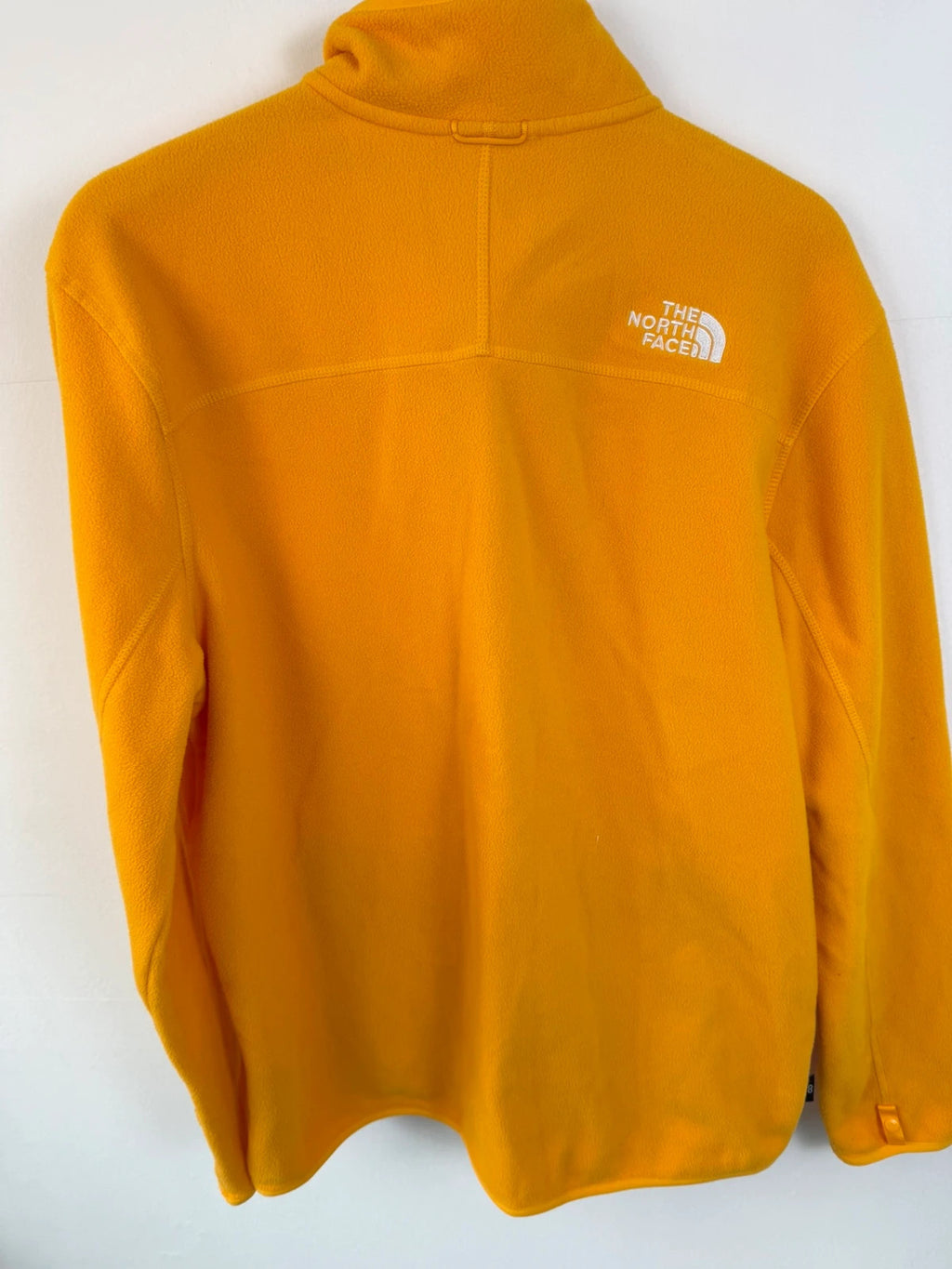 The North Face yellow fleece jacket with embroidered logo and zippered pockets.