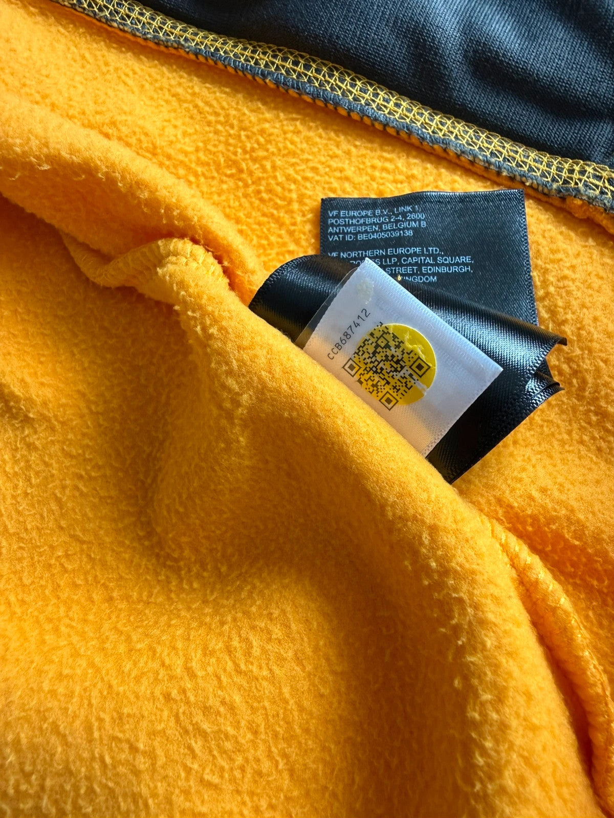 The North Face yellow fleece jacket with embroidered logo and zippered pockets.