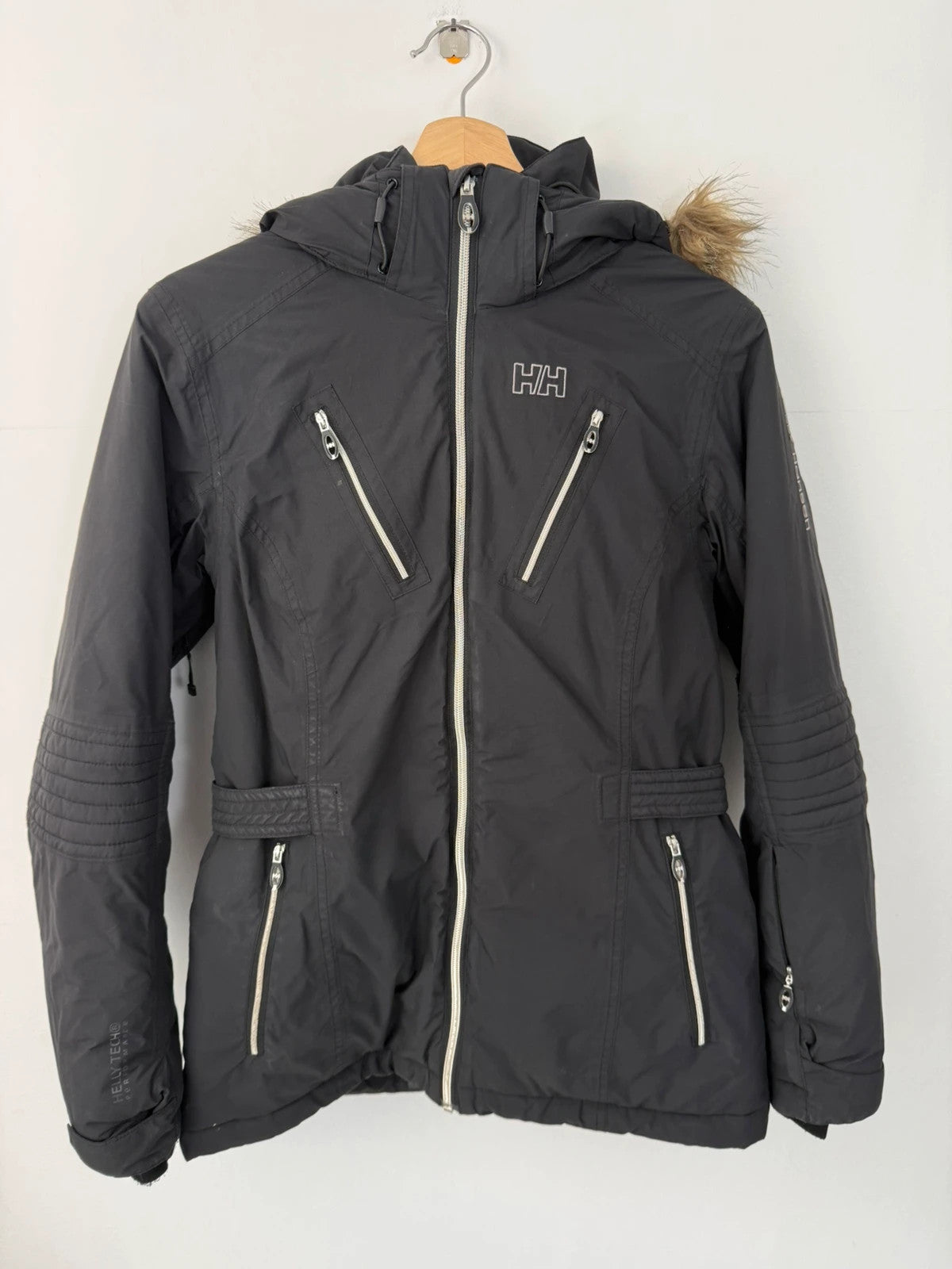 Helly Hansen black ski jacket with detachable faux trim hood and zip pockets.