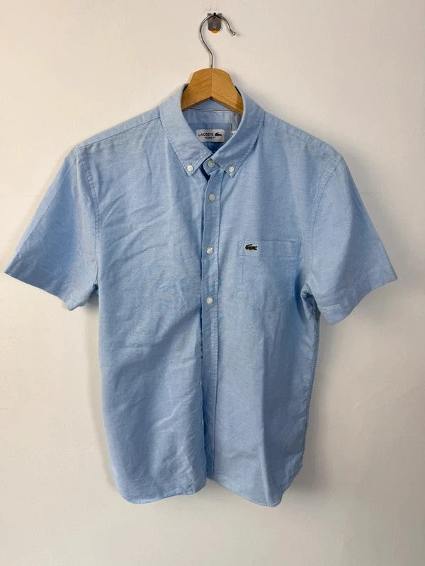 Lacoste light blue short sleeve Oxford shirt with embroidered crocodile logo and button-down collar.
