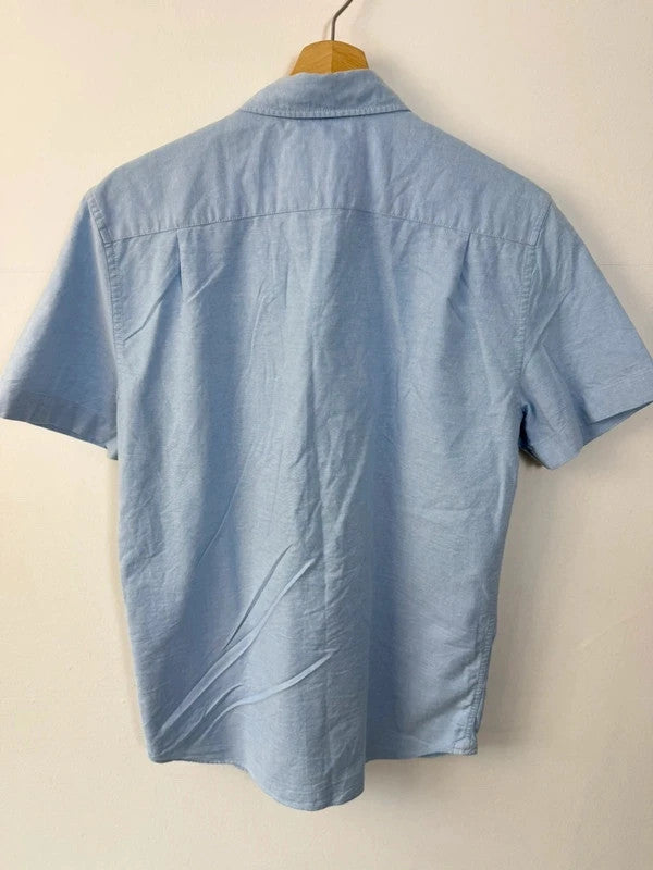 Lacoste light blue short sleeve Oxford shirt with embroidered crocodile logo and button-down collar.
