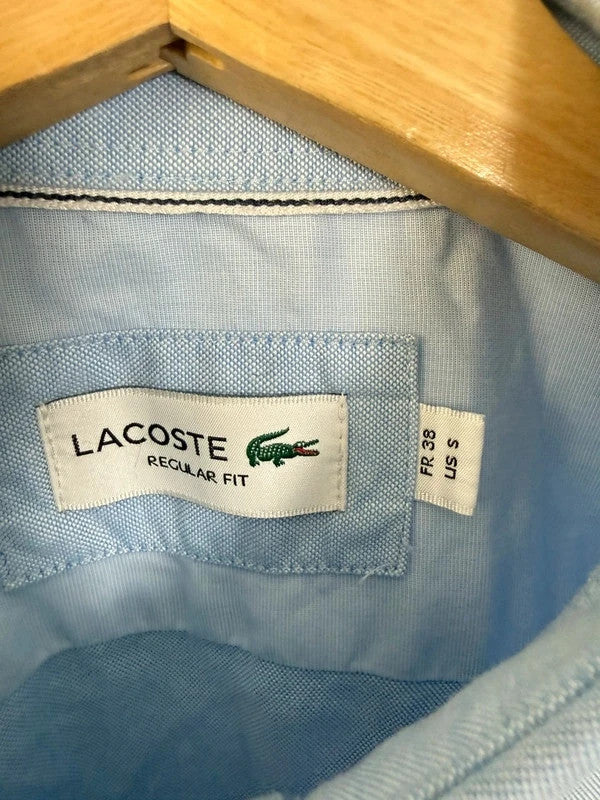 Lacoste light blue short sleeve Oxford shirt with embroidered crocodile logo and button-down collar.