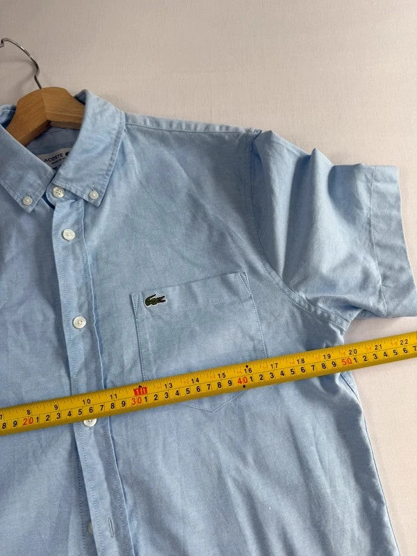 Lacoste light blue short sleeve Oxford shirt with embroidered crocodile logo and button-down collar.