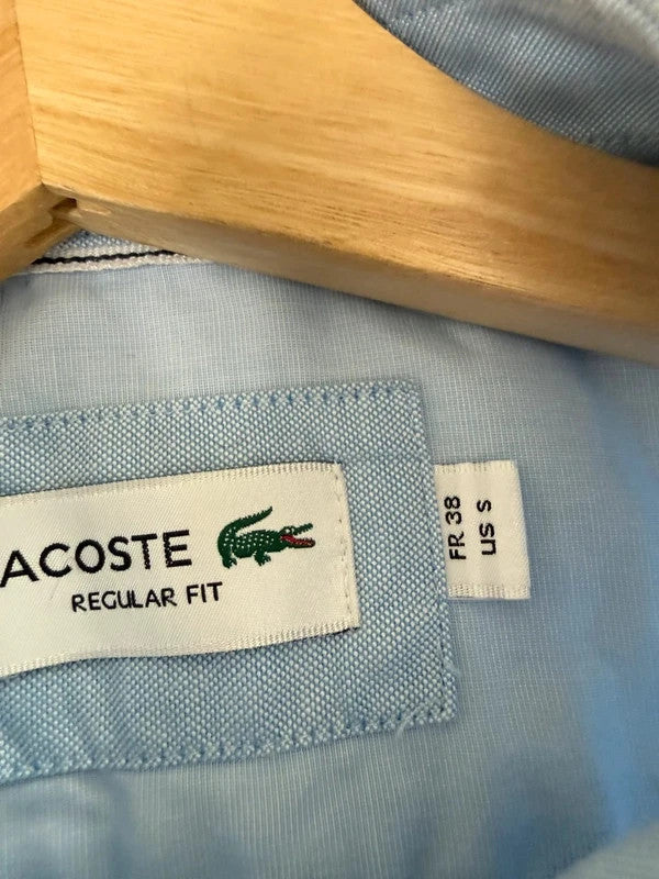 Lacoste light blue short sleeve Oxford shirt with embroidered crocodile logo and button-down collar.