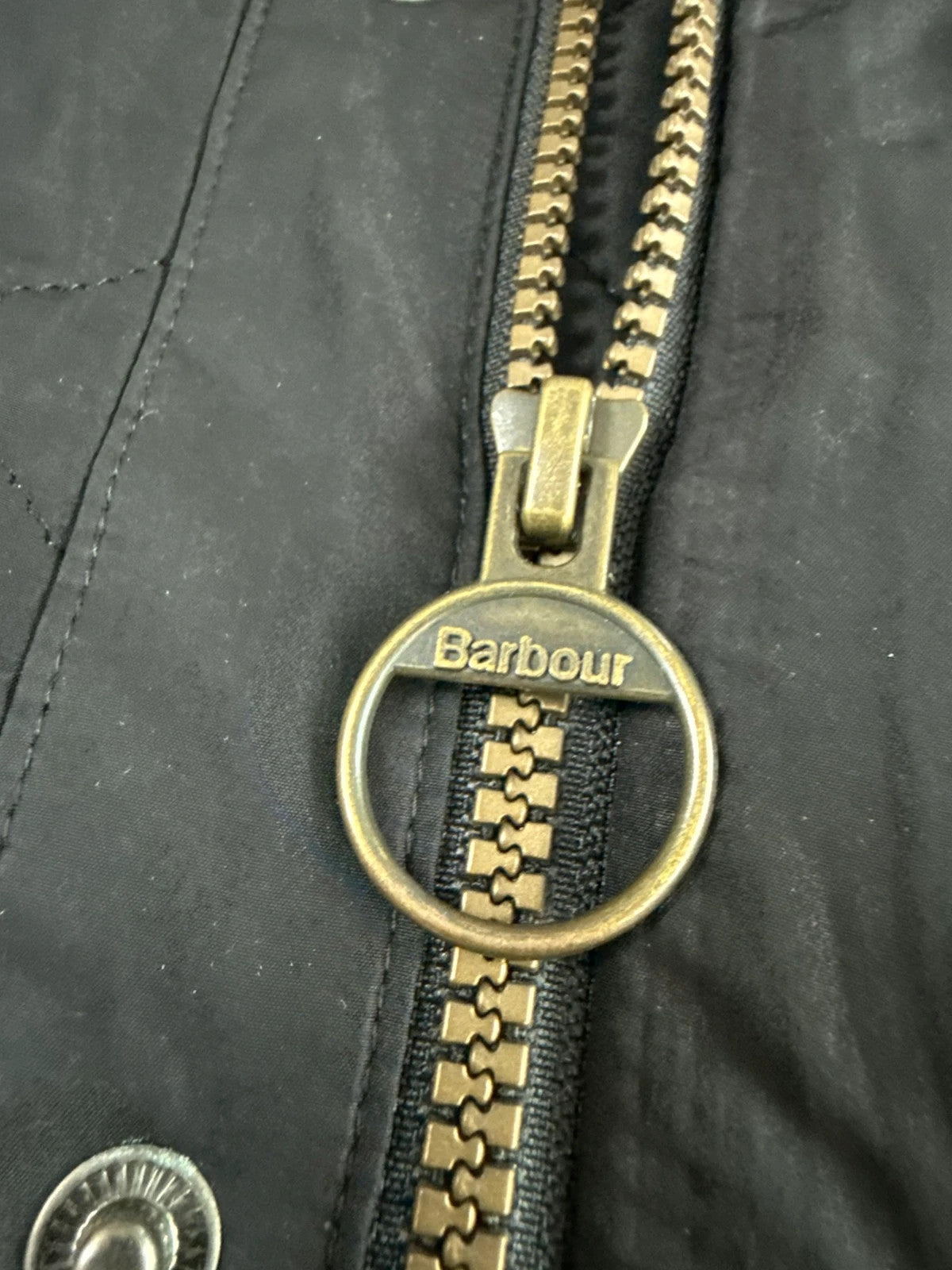 Barbour black quilted jacket with corduroy collar and three front pockets.