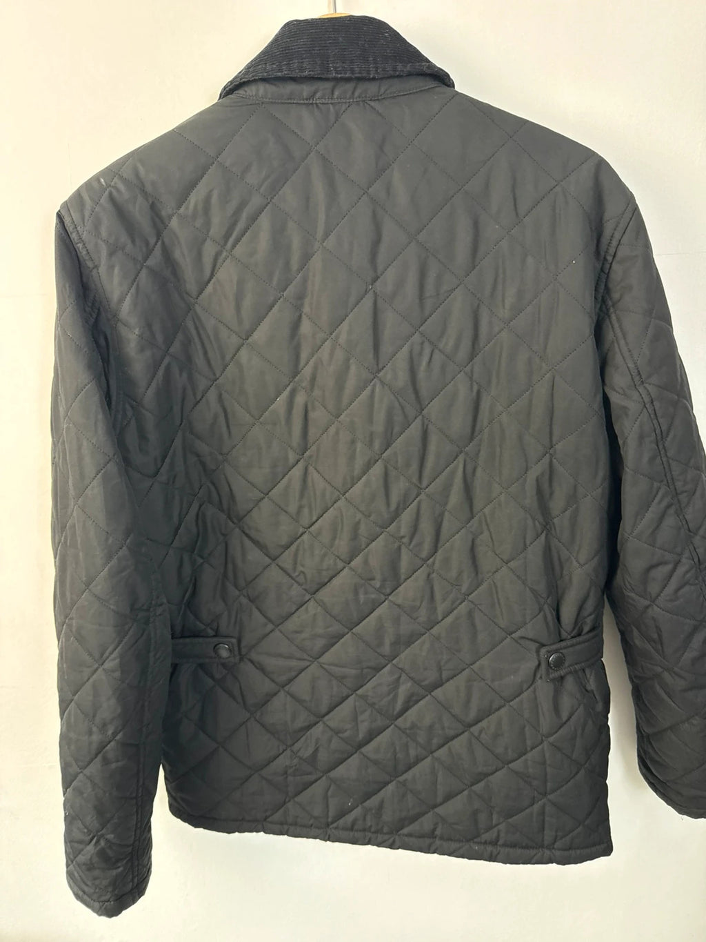 Barbour black quilted jacket with corduroy collar and three front pockets.