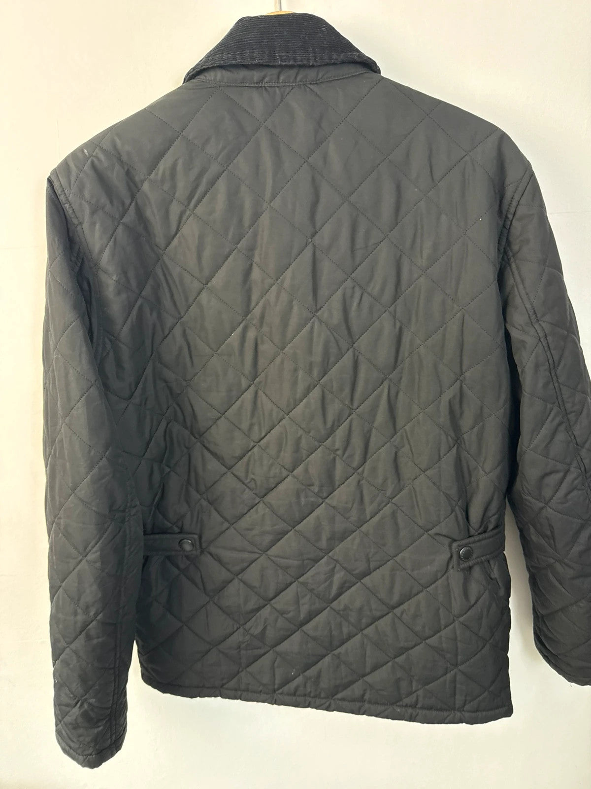 Barbour black quilted jacket with corduroy collar and three front pockets.