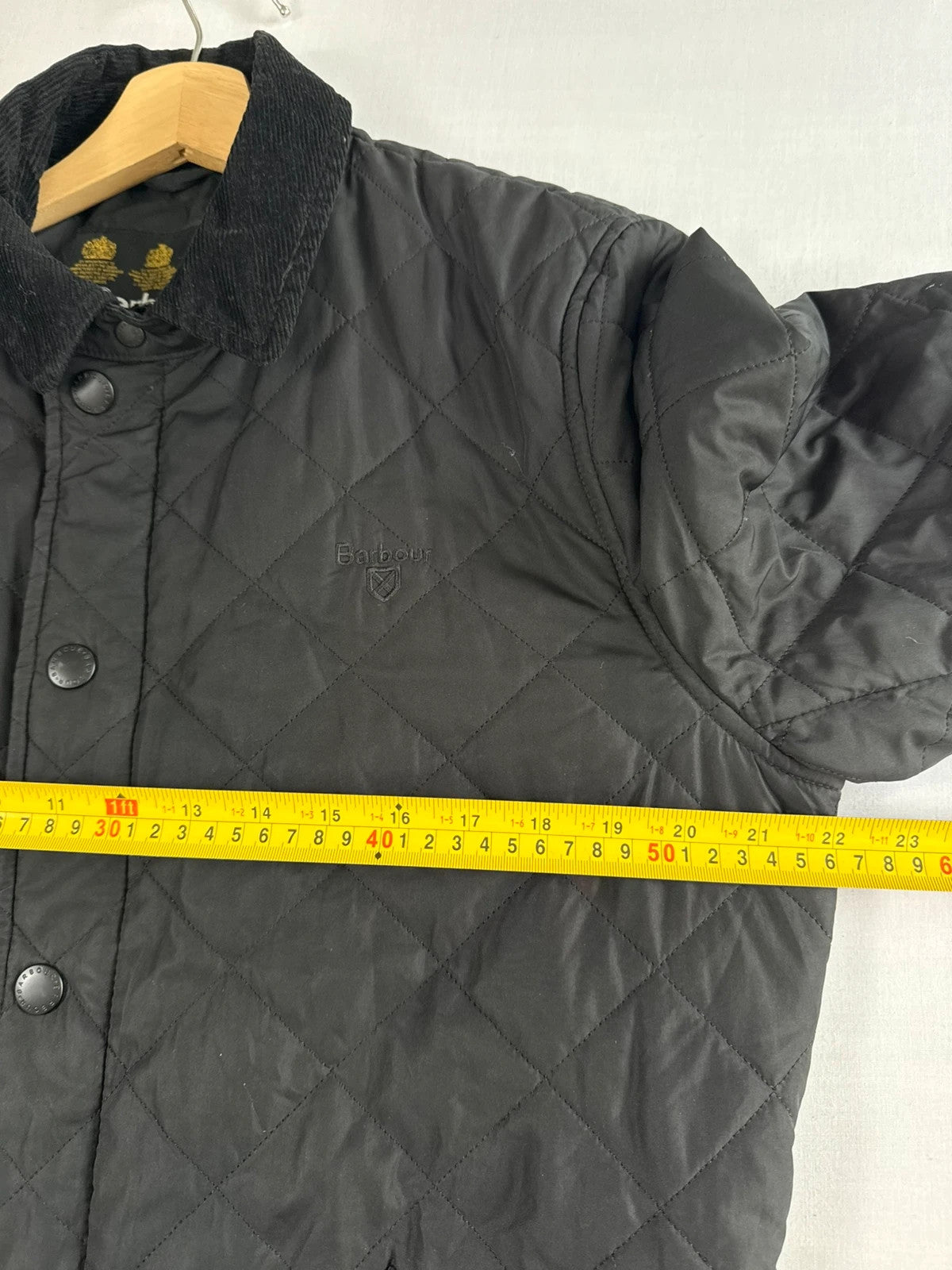 Barbour black quilted jacket with corduroy collar and three front pockets.