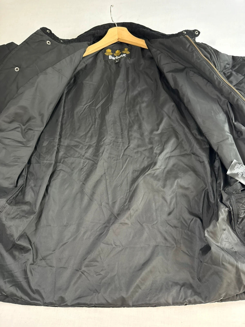 Barbour black quilted jacket with corduroy collar and three front pockets.