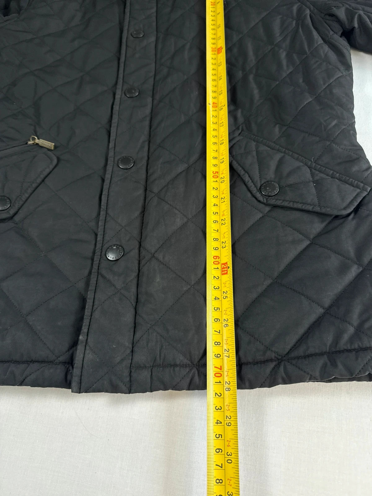 Barbour black quilted jacket with corduroy collar and three front pockets.