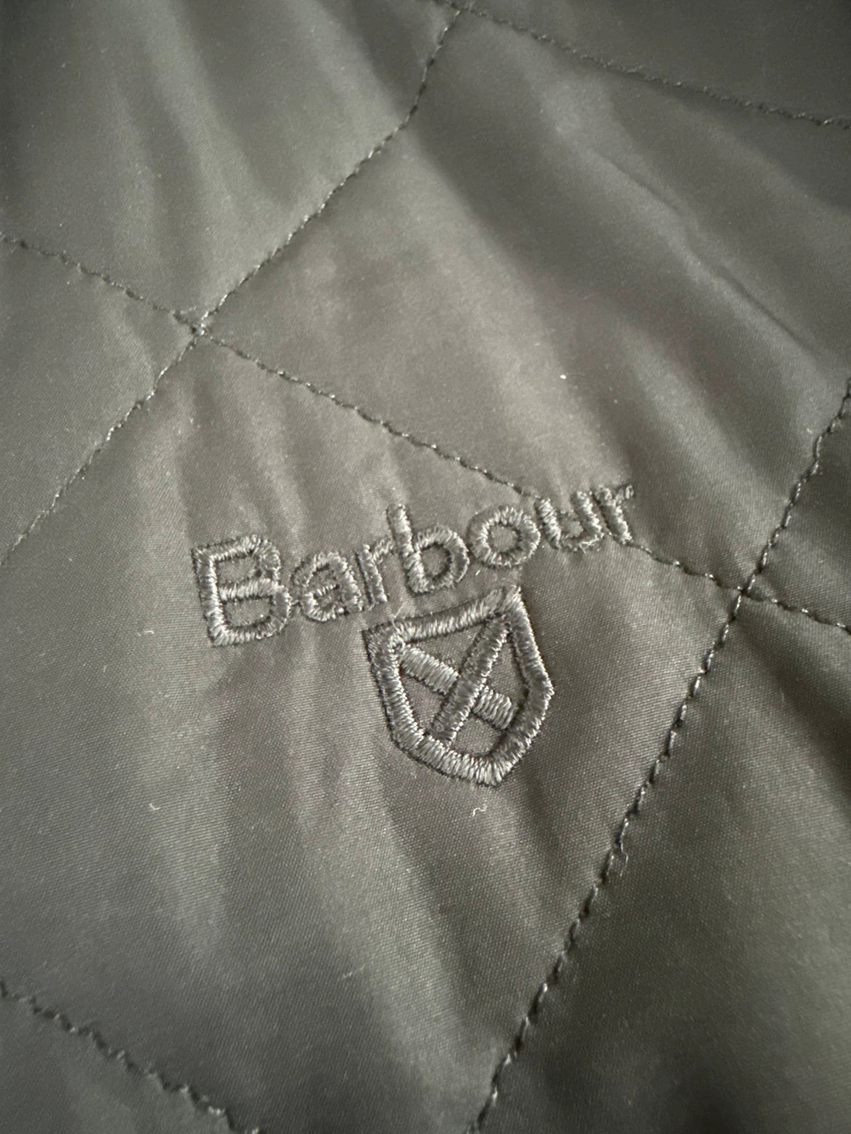 Barbour black quilted jacket with corduroy collar and three front pockets.