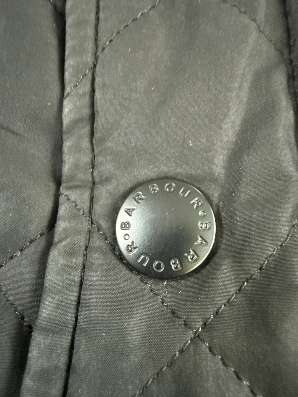 Barbour black quilted jacket with corduroy collar and three front pockets.