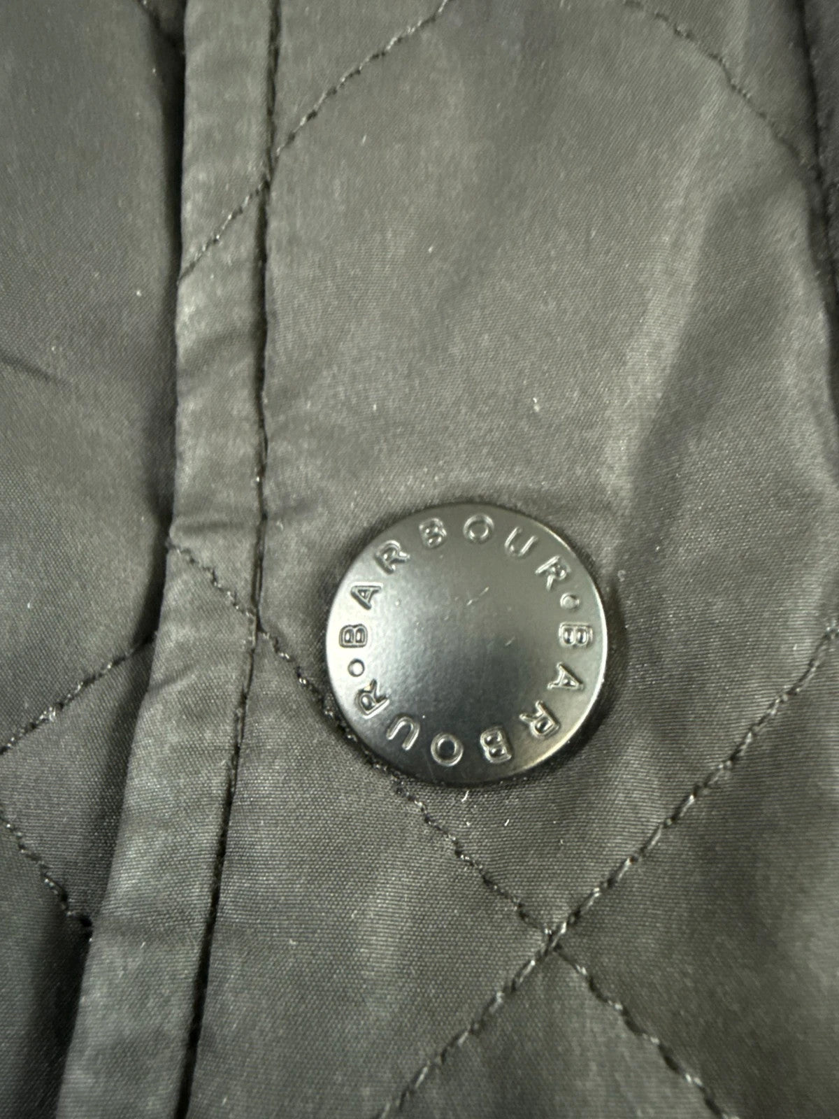 Barbour black quilted jacket with corduroy collar and three front pockets.
