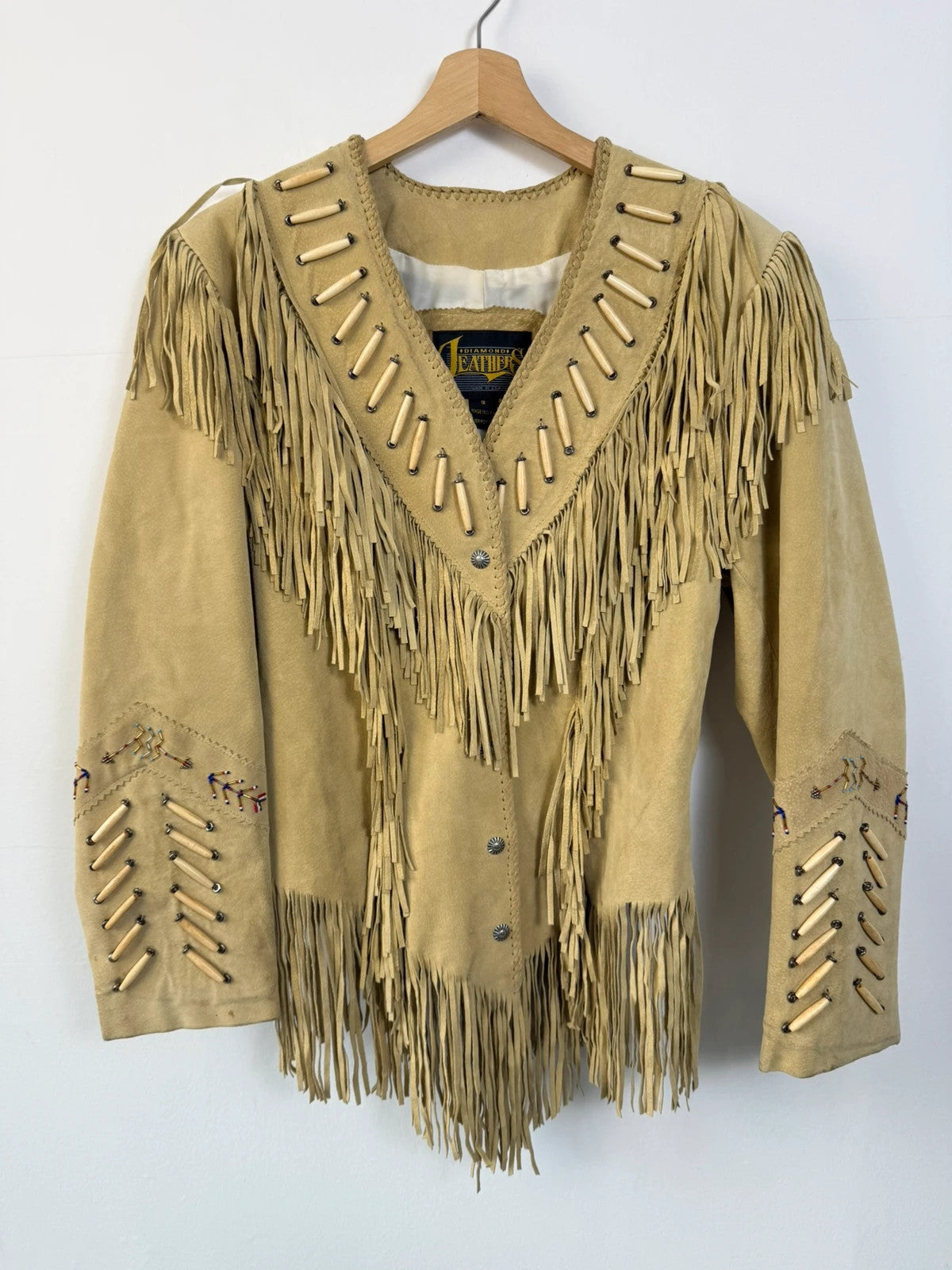 Diamond Leathers tan suede jacket with fringe, beaded arrow detailing, and snap closure.